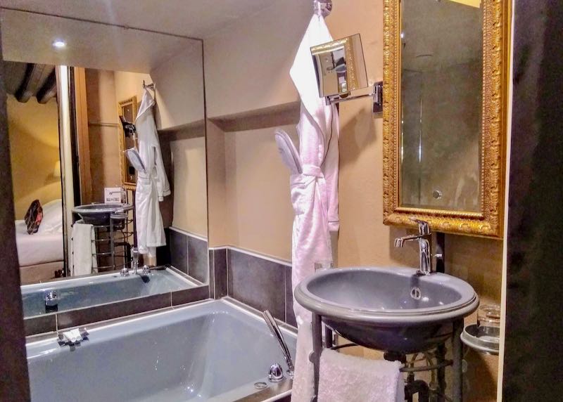El baño tiene una bañera y un espejo ornamentado.