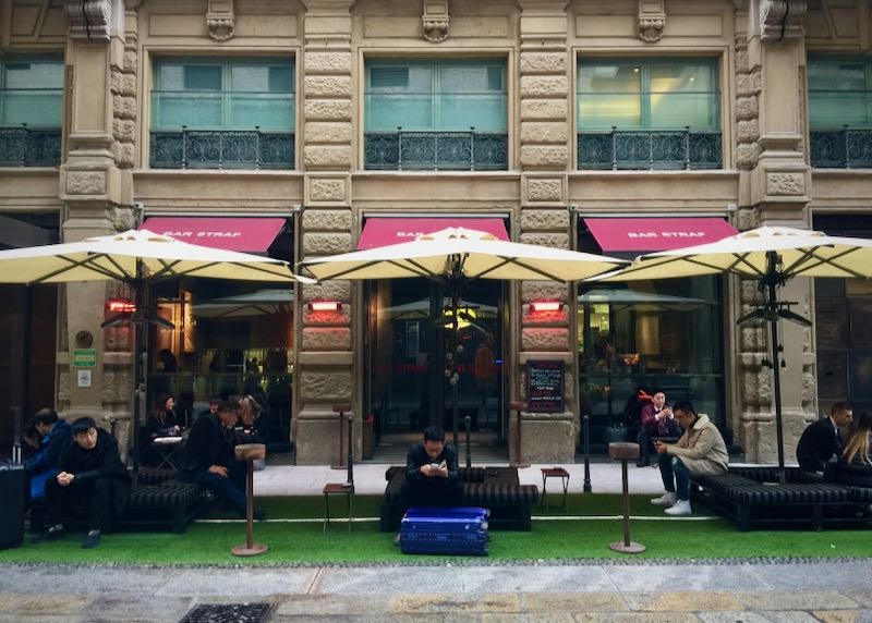 Los clientes se sientan bajo las sombrillas fuera de un bar en Milán