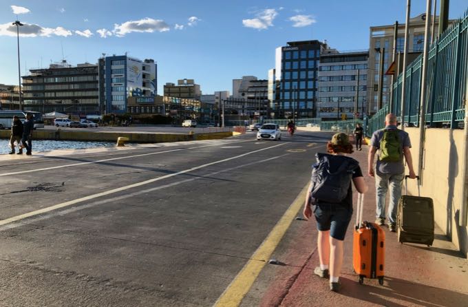 Un hombre y una niña con maletas, caminando por una carretera del puerto