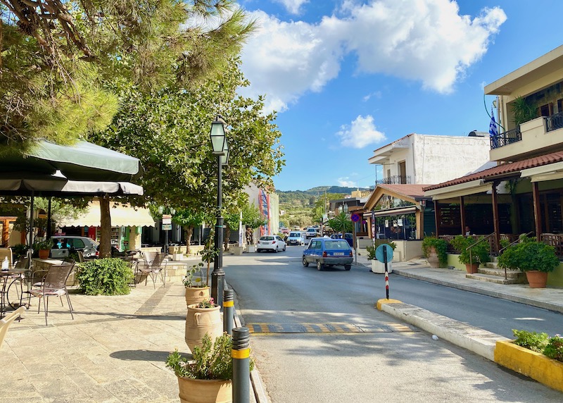 La calle principal a través de Archanes con una plaza llena de árboles en Creta
