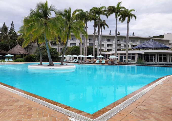 Gran piscina con isla de palmeras en Le Méridien Noumea Resort & Spa, ideal para niños.
