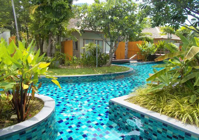 Jardines tropicales y piscina envolvente en un complejo tranquilo