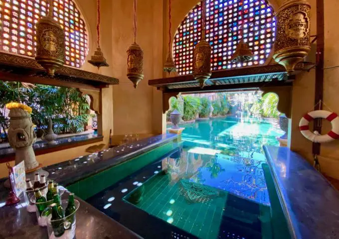 Piscina interior y exterior con bar en la piscina, rodeada de faroles colgantes